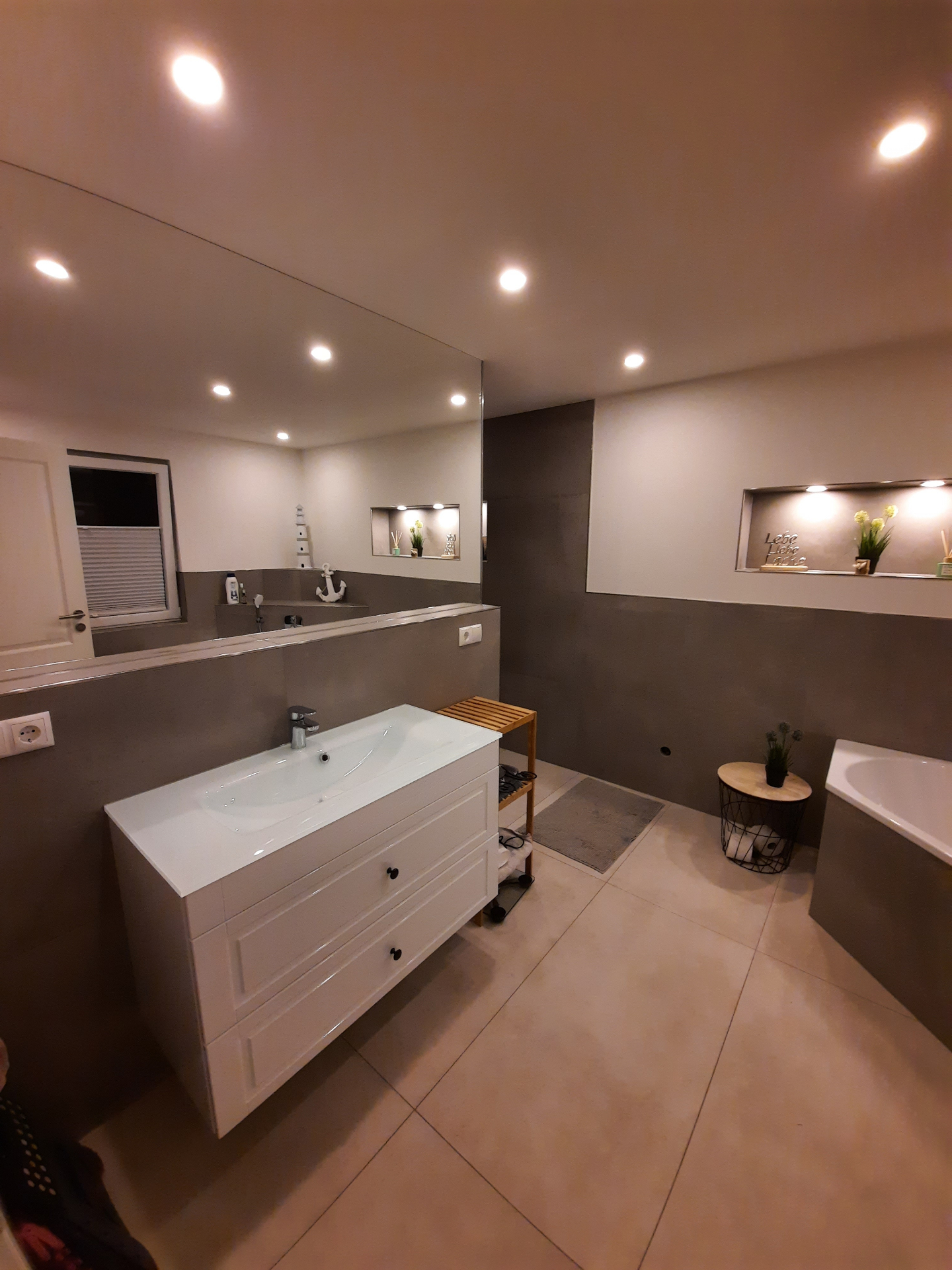 Modernes Badezimmer mit großformatigen grauen Wandfliesen, Waschplatz und indirekter Deckenbeleuchtung