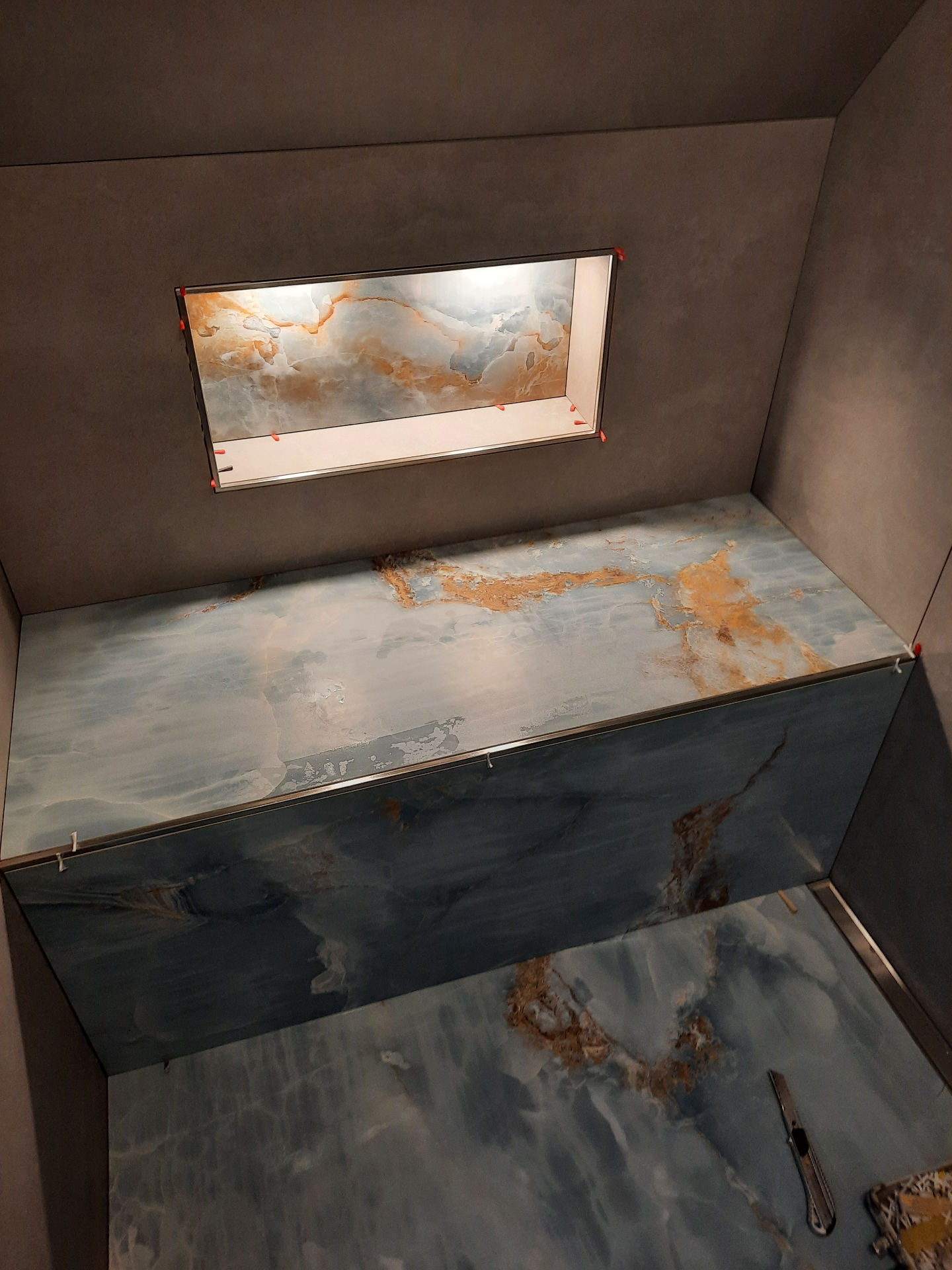 Duschnische mit blau-goldenen Marmor-Fliesen und dunkelgrauer Wandgestaltung
